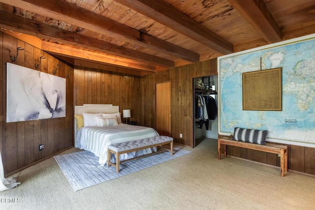carpeted bedroom featuring wooden ceiling, wooden walls, beam ceiling, a walk in closet, and baseboards