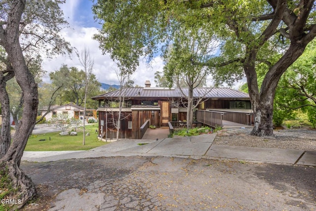 back of property featuring metal roof, a chimney, a lawn, and a porch