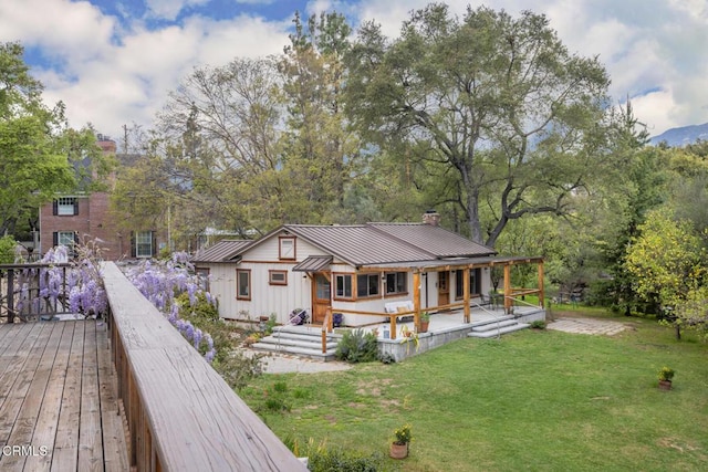 view of front of property with a chimney, a front lawn, metal roof, a standing seam roof, and board and batten siding