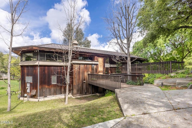 rear view of property with metal roof, a lawn, a standing seam roof, and a chimney