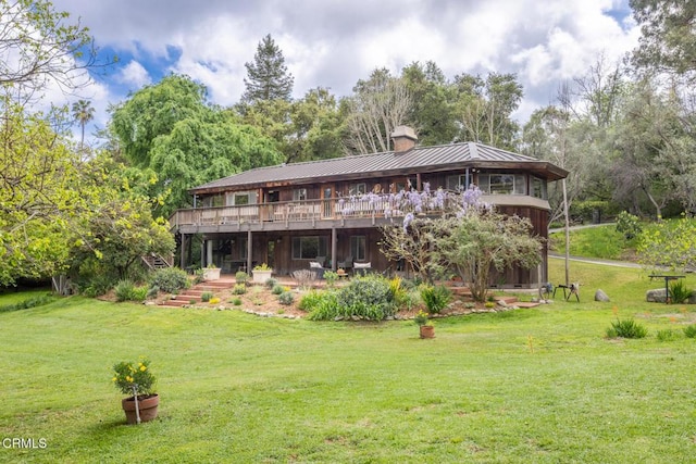 back of house with a chimney, a wooden deck, a yard, a standing seam roof, and metal roof
