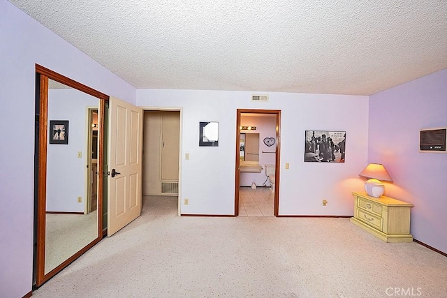 bedroom with a textured ceiling, baseboards, and ensuite bathroom