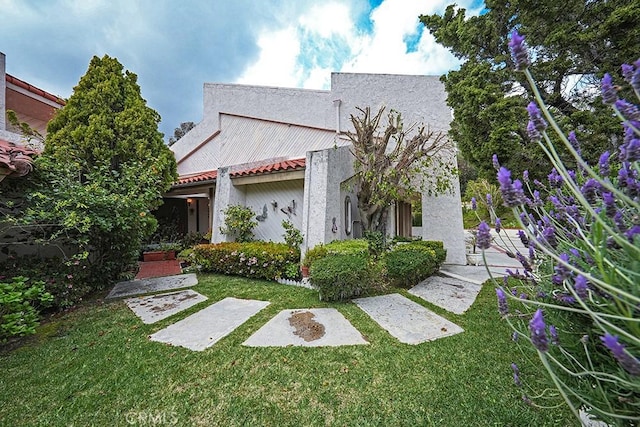 rear view of house with a yard and stucco siding