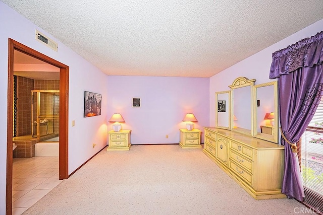 bedroom featuring a textured ceiling, baseboards, light carpet, and ensuite bathroom