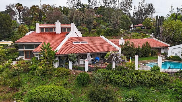 back of property with a tile roof, a chimney, fence, a patio, and a pool with connected hot tub