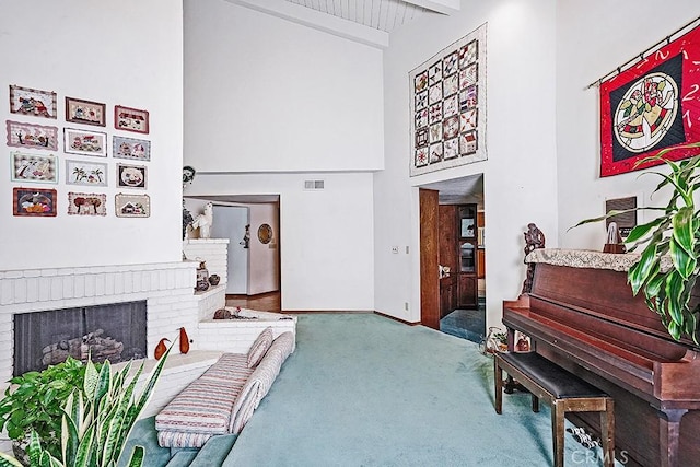 living area with a high ceiling, carpet, a fireplace, beam ceiling, and baseboards