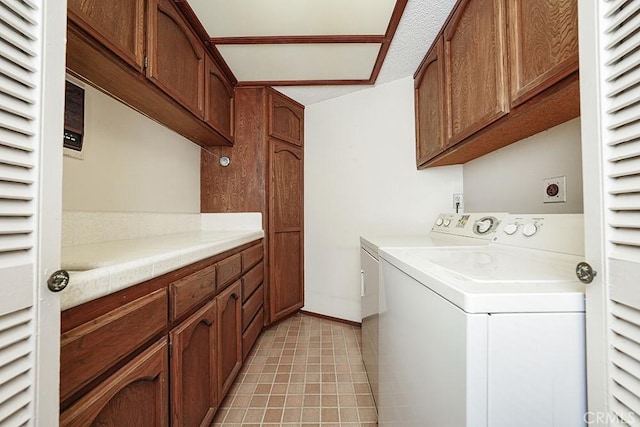 laundry area with cabinet space, washing machine and dryer, baseboards, and light tile patterned floors