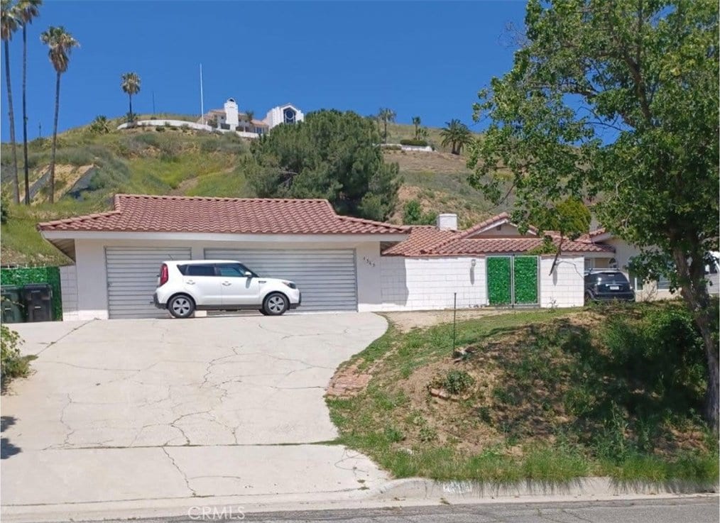 view of front of house with a tile roof, a garage, driveway, and stucco siding