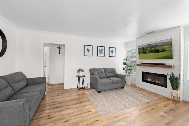5927 Mckinley Ave, South Gate, CA 90280 - living area featuring light wood finished floors, a glass covered fireplace, ornamental molding, and baseboards
