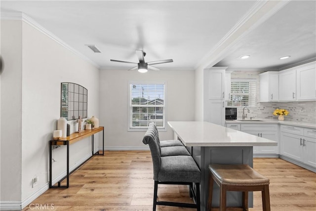 5927 Mckinley Ave, South Gate, CA 90280 - kitchen featuring a sink, healthy amount of natural light, a breakfast bar area, light wood-style flooring, and crown molding