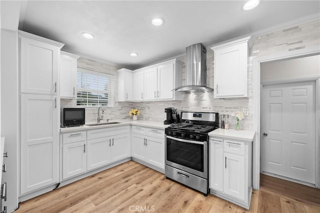 5927 Mckinley Ave, South Gate, CA 90280 - kitchen featuring gas range, wall chimney exhaust hood, a sink, light countertops, and white cabinetry