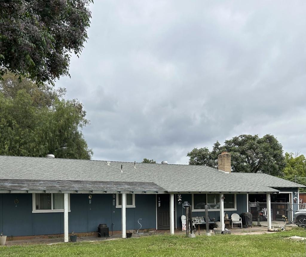 rear view of property with roof with shingles and a chimney