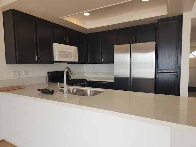 600 N The Strand Unit 12, Oceanside, CA 92054 - kitchen with white microwave, stainless steel fridge, a raised ceiling, recessed lighting, and dark cabinetry