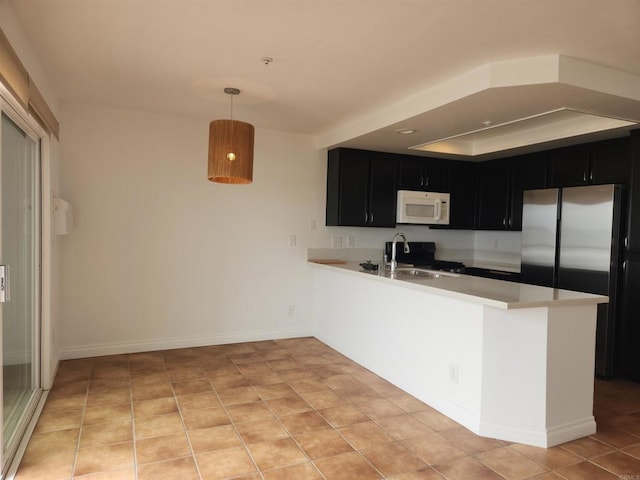 600 N The Strand Unit 12, Oceanside, CA 92054 - kitchen with white microwave, dark cabinets, light countertops, a peninsula, and a sink