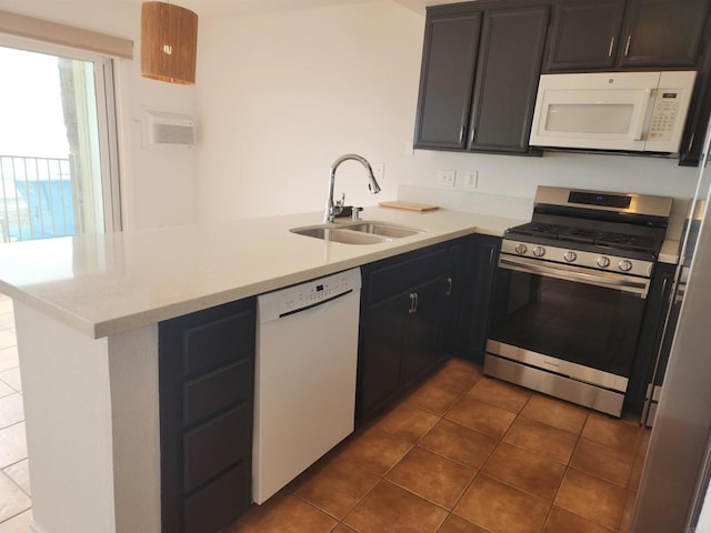 600 N The Strand Unit 12, Oceanside, CA 92054 - kitchen with white appliances, a sink, a peninsula, and dark tile patterned flooring