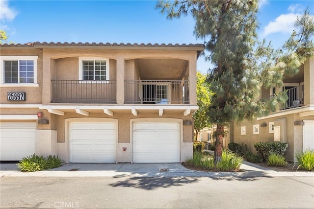 25892 Iris Ave Unit A, Moreno Valley, CA 92551 - townhome / multi-family property featuring a balcony, stucco siding, an attached garage, and driveway