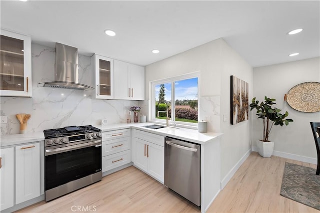 27751 Via Lorca, Mission Viejo, CA 92692 - kitchen with stainless steel appliances, wall chimney range hood, a sink, light wood finished floors, and decorative backsplash