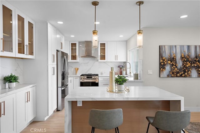 27751 Via Lorca, Mission Viejo, CA 92692 - kitchen featuring stainless steel appliances, wall chimney range hood, decorative backsplash, light wood-style flooring, and a kitchen bar