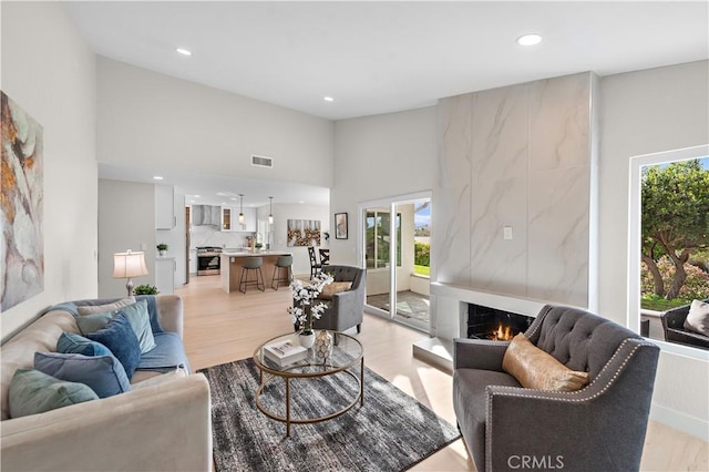 27751 Via Lorca, Mission Viejo, CA 92692 - living room featuring a lit fireplace, light wood-style floors, recessed lighting, and high vaulted ceiling
