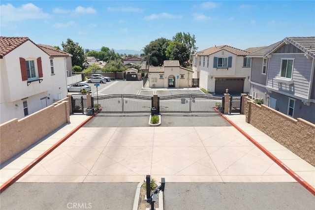 view of concrete road with a gate, a residential view, a gated entry, curbs, and sidewalks