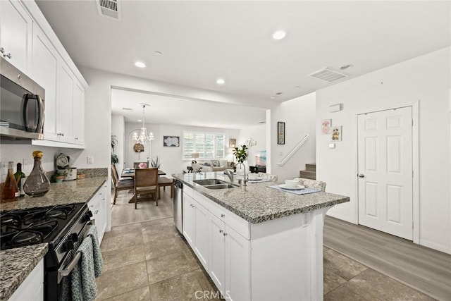 kitchen with a sink, stainless steel microwave, white cabinetry, recessed lighting, and light stone countertops