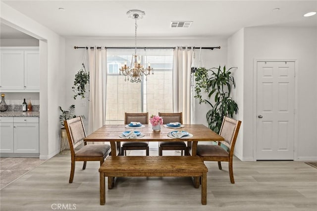 dining space with light wood-type flooring, a chandelier, and baseboards