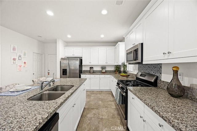 kitchen featuring stainless steel appliances, a sink, white cabinets, light stone counters, and recessed lighting