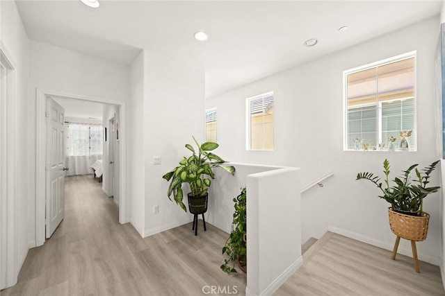 hall with light wood-style floors, baseboards, recessed lighting, and an upstairs landing