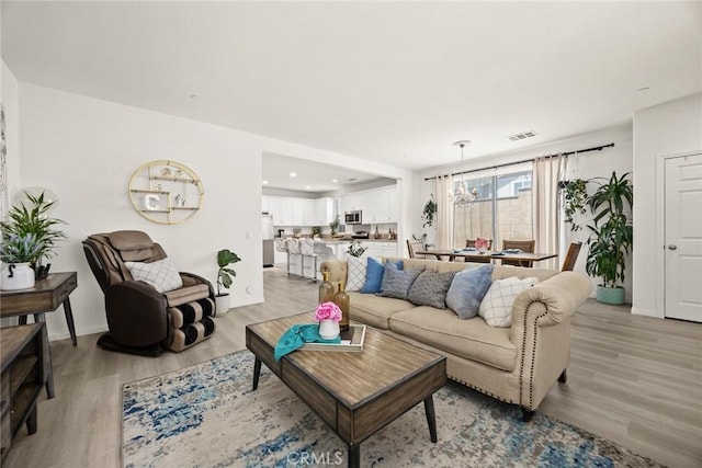 living area featuring light wood finished floors, baseboards, and recessed lighting