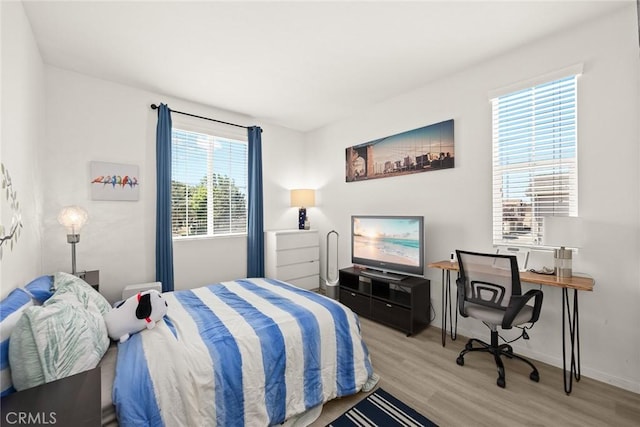 bedroom featuring light wood-style flooring, baseboards, and an office area