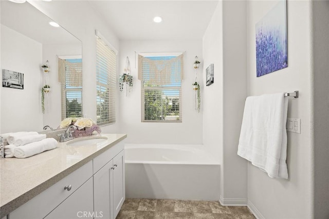 full bath with vanity, a bath, recessed lighting, and baseboards