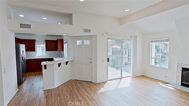 137 Corsica Dr, Newport Beach, CA 92660 - kitchen featuring stainless steel fridge, light wood-type flooring, reddish brown cabinets, a peninsula, and a kitchen bar