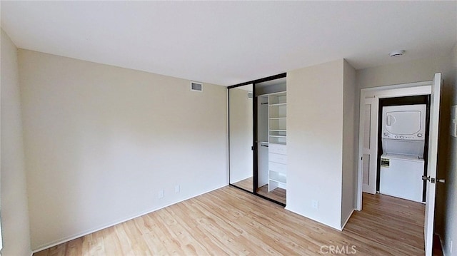 137 Corsica Dr, Newport Beach, CA 92660 - unfurnished bedroom featuring stacked washer and clothes dryer, wood finished floors, and a closet