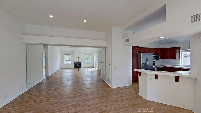 137 Corsica Dr, Newport Beach, CA 92660 - kitchen with stainless steel appliances, open floor plan, light wood-style floors, a peninsula, and reddish brown cabinets