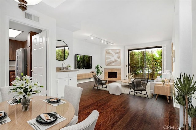 18600 Clark St Unit 102, Tarzana, CA 91356 - dining space featuring dark wood-style flooring, a fireplace with raised hearth, and rail lighting