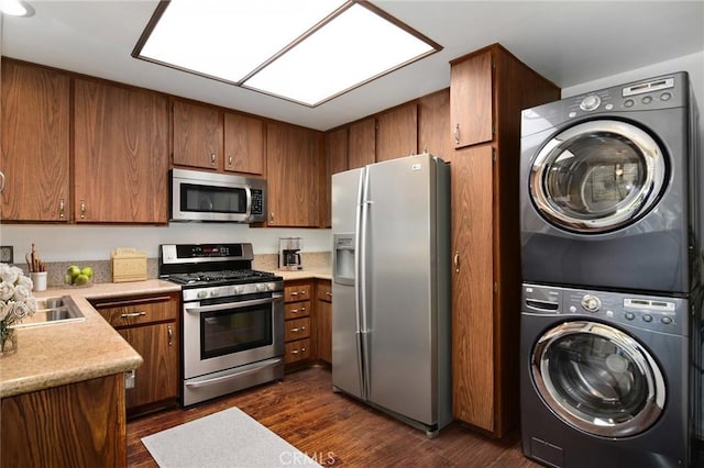 18600 Clark St Unit 102, Tarzana, CA 91356 - kitchen featuring appliances with stainless steel finishes, stacked washer and clothes dryer, dark wood-style floors, light countertops, and brown cabinetry