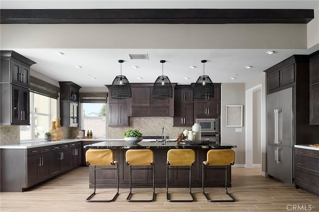 16402 Ginger Creek Dr, Riverside, CA 92504 - kitchen with stainless steel appliances, light wood-style flooring, tasteful backsplash, a kitchen bar, and hanging light fixtures