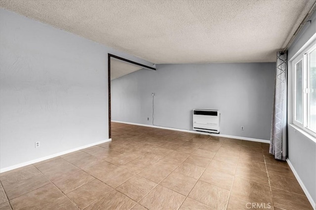 5799 Halsey Ave Unit 29, Palms, CA 92277 - spare room with heating unit, a textured ceiling, baseboards, vaulted ceiling, and tile patterned flooring