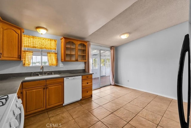 5799 Halsey Ave Unit 29, Palms, CA 92277 - kitchen with white dishwasher, a sink, stove, brown cabinetry, and dark countertops