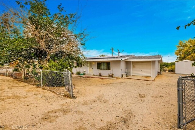 5799 Halsey Ave Unit 29, Palms, CA 92277 - back of property featuring a garage, solar panels, stucco siding, and fence
