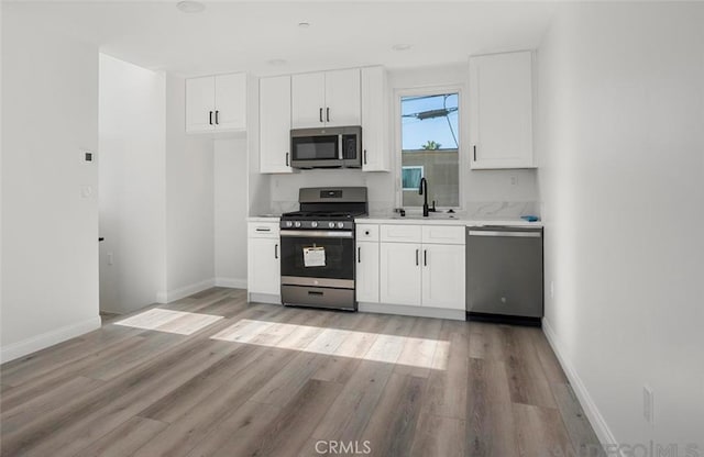 4048 Cherokee Ave, San Diego, CA 92104 - kitchen featuring appliances with stainless steel finishes, a sink, white cabinetry, light wood-style floors, and light countertops