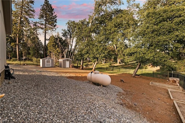 1612 San Jose Ln, Paradise, CA 95969 - yard at dusk with a storage unit and view of wooded area
