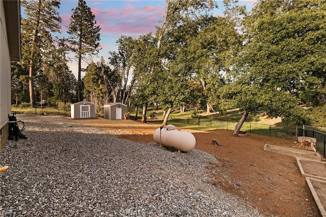 1612 San Jose Ln, Paradise, CA 95969 - yard at dusk with a storage shed, an outbuilding, fence, and view of scattered trees