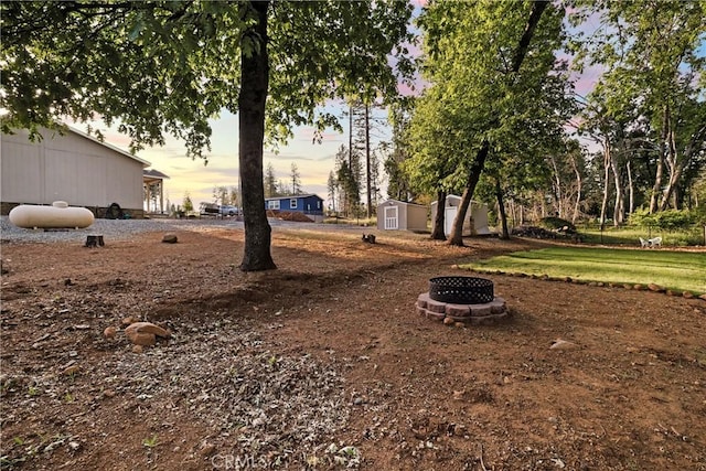 1612 San Jose Ln, Paradise, CA 95969 - yard at dusk with an outdoor fire pit, a storage shed, and an outdoor structure
