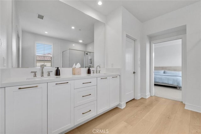 107 Plum Lily, Irvine, CA 92618 - ensuite bathroom featuring wood finished floors, a stall shower, double vanity, recessed lighting, and baseboards