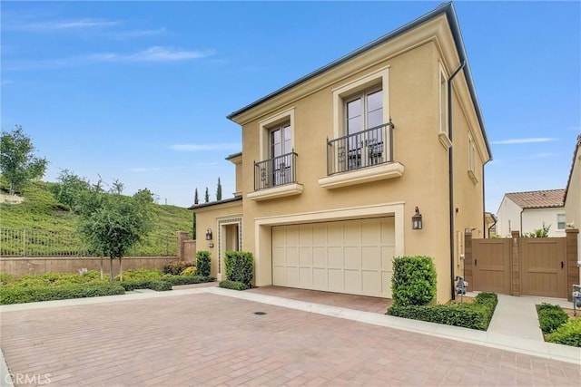 107 Plum Lily, Irvine, CA 92618 - view of front facade with a balcony, stucco siding, an attached garage, and fence