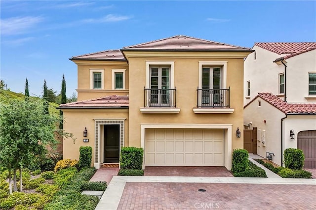 107 Plum Lily, Irvine, CA 92618 - mediterranean / spanish-style house with a balcony, an attached garage, stucco siding, and a tile roof