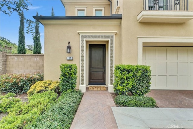 107 Plum Lily, Irvine, CA 92618 - view of exterior entry with stucco siding, fence, a garage, and a balcony