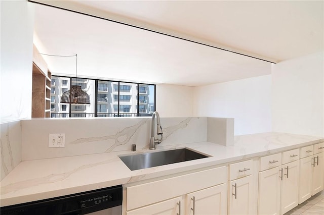 kitchen with a sink, stainless steel dishwasher, light stone counters, and white cabinetry