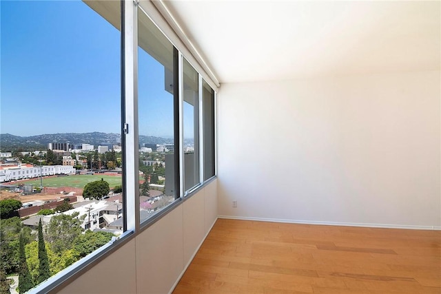 spare room featuring light wood-style floors, plenty of natural light, and baseboards